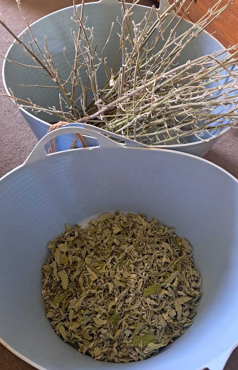 Two large flexi tubs. One is filled with bare sticks, and the other with a fairly thin layer of dried catnip leaves.